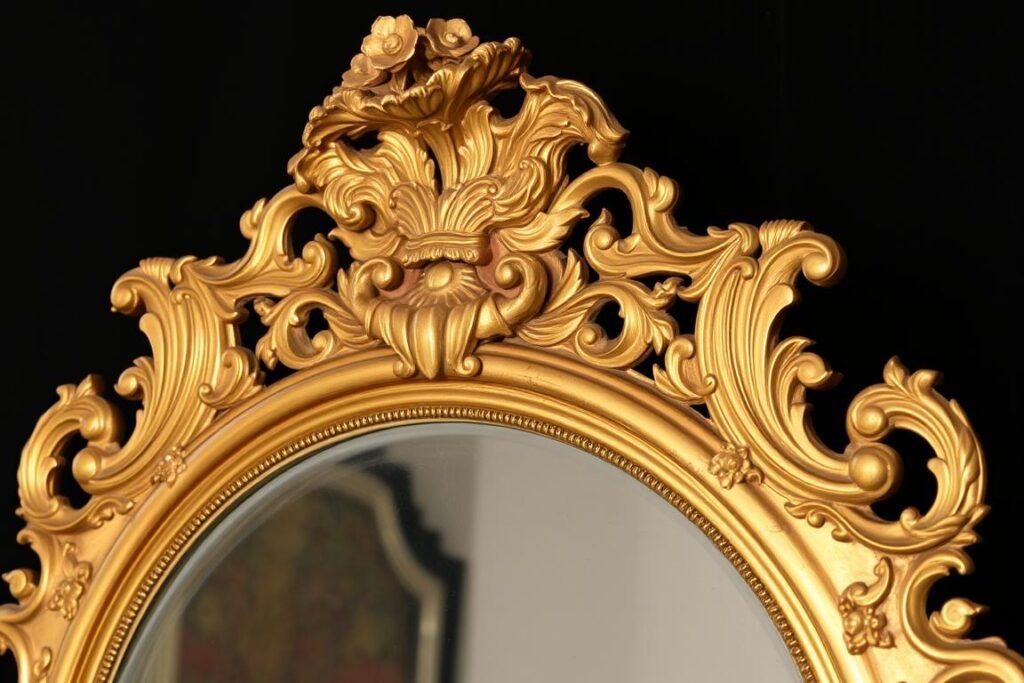 An ornate Victorian-era mirror with intricate gold frame and detailed floral embellishments An ornate Victorian-era mirror with intricate gold frame and detailed floral embellishments
