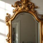Ornate gold gilt antique mirror with aged patina reflecting soft light in an elegant entryway
