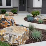 Transform Your Outdoor Space: Creative Ideas for Landscaping with Rocks A beautifully landscaped front yard featuring various sizes of rocks, boulders, and drought-resistant plants creating a natural, flowing landscape design