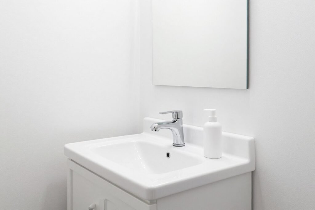 All-white bathroom featuring a white vanity with subtle texture variations