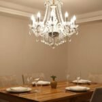 Elegant dining room with a crystal chandelier hanging over a wooden table set for dinner, creating a warm and inviting atmosphere