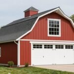 Classic red barn style garage with white trim, gambrel roof, and sliding doors showcasing traditional barn architecture