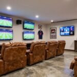 Sports-themed man cave garage with multiple screens, team memorabilia, and comfortable seating