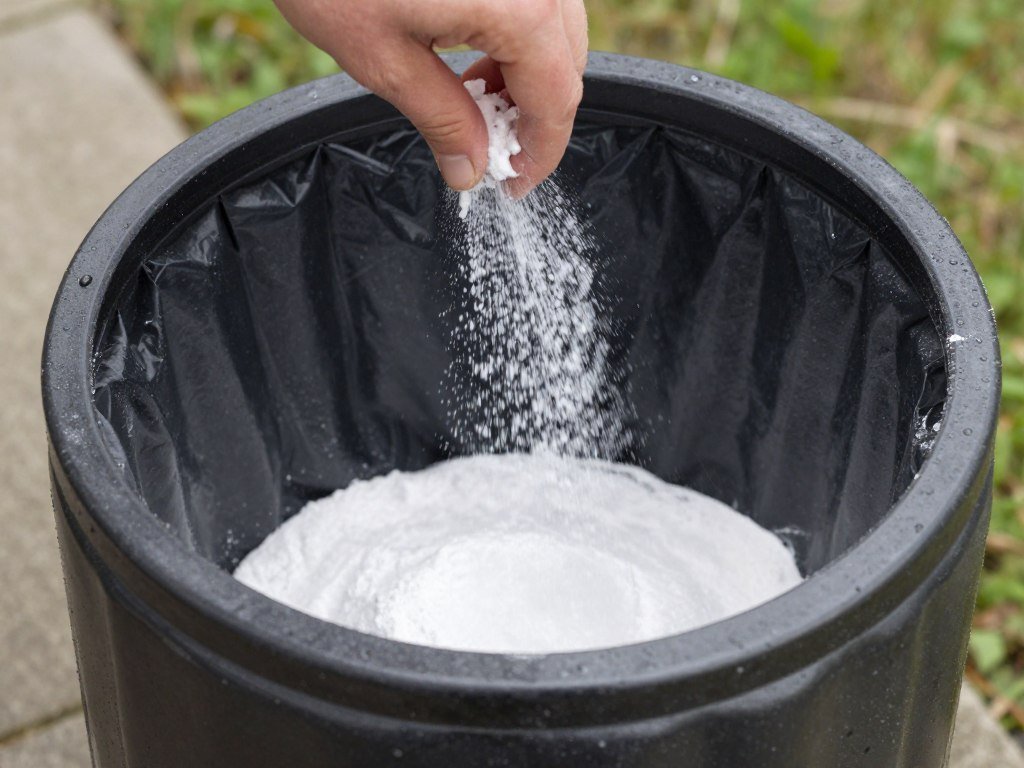 Sprinkling baking soda in trash can